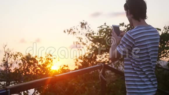 在美丽的日落时分年轻人在山上使用手机在缓慢的运动中产生了密集的耀斑效应1920x1080视频的预览图