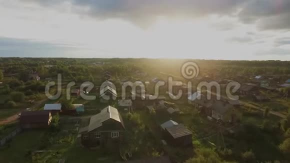 在一个晴朗的日子飞越森林里的村庄四方直升机4K视频的预览图