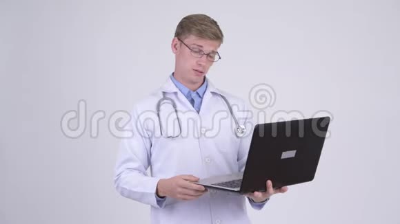 快乐的年轻英俊的医生在用笔记本电脑思考视频的预览图