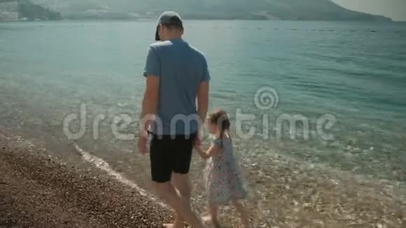 爸爸和他的小女儿正沿着海边散步视频的预览图