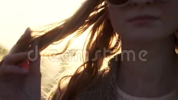 黎明时美丽女孩的特写肖像一个年轻的女人摸头发太阳光线和眩光慢动作视频的预览图