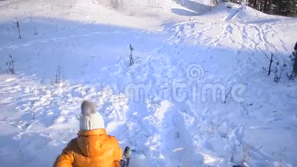 少年女孩在冬雪公园的一座小山上滑着雪一只狗在和一个开朗的女孩玩耍视频拍摄在移动视频的预览图