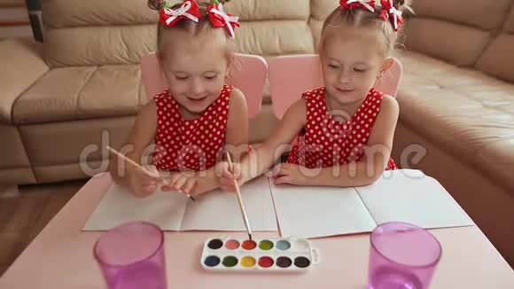 两个小妹妹双胞胎很高兴和坐在桌子旁的水彩画视频的预览图