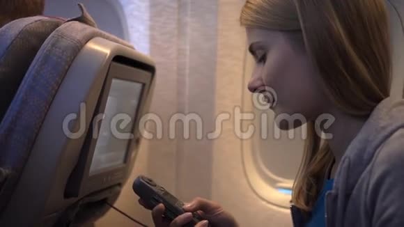 飞机窗户附近美丽迷人的女人长途飞行使用车载电视屏幕视频的预览图