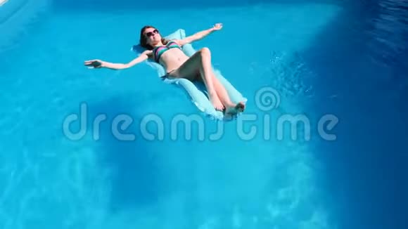 千禧一代女孩在游泳池节日酒店海滩上漂浮夏天戴着墨镜微笑晒太阳视频的预览图
