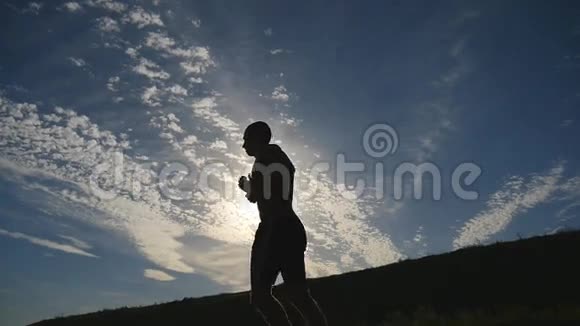 日落时分在乡间慢跑的人的剪影男子慢跑马拉松训练运动员运动和视频的预览图