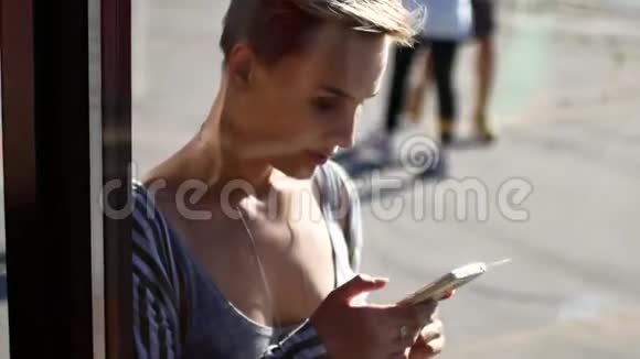 一个女孩正在看她的手机这段视频是通过咖啡馆的橱窗拍摄的女人在社交中交流视频的预览图