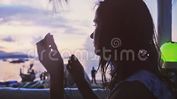 少女戴耳机坐在咖啡馆海滩听音乐日落慢动作1920x1080视频的预览图