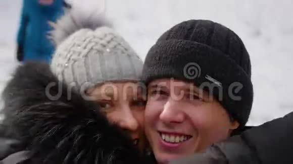那个和女孩在一起的家伙在冬季公园里用相机拍摄自己纺纱视频的预览图