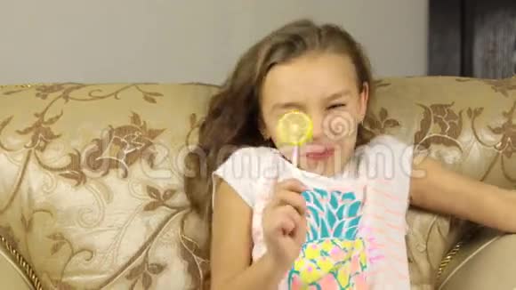 女孩舔着柠檬形状的棒子上的糖果她很酸视频的预览图
