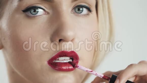 特写镜头女人脸和化妆刷在嘴唇上涂上红色口红金发年轻的白种人模特视频的预览图