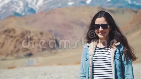 美丽的女孩对大自然微笑和笑在这座山的背景下视频的预览图