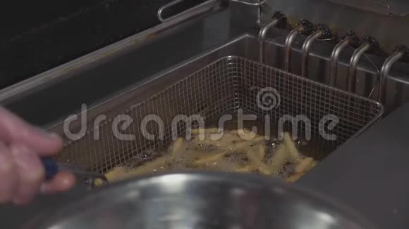 厨师在商业厨房的钢碗里倒入准备好的炸薯条视频的预览图