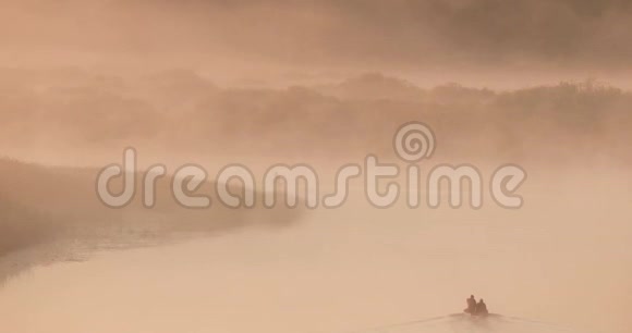 平静的湖泊河流和人钓鱼从古老的木制划船渔船在美丽的薄雾日出在夏天的早晨视频的预览图