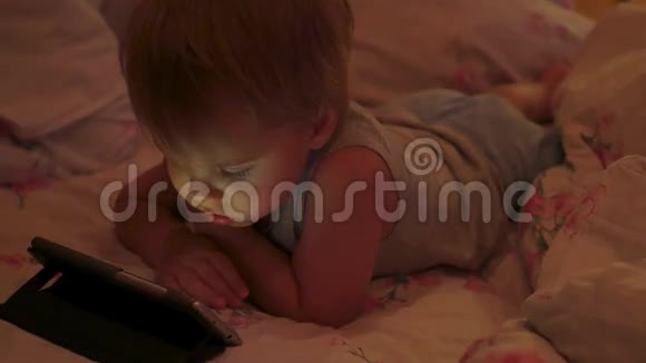 一个小男孩深夜在智能手机里看动画片视频的预览图