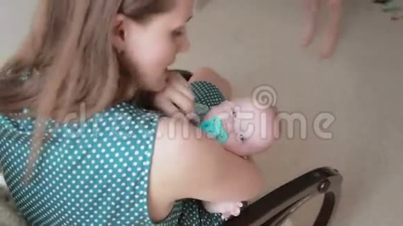 姐姐亲吻她刚出生的弟弟他妈妈坐在摇椅上抱着她视频的预览图