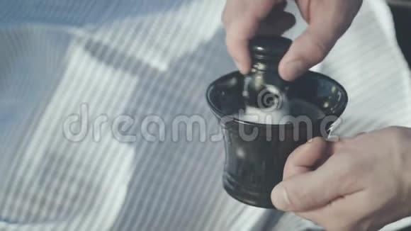 陶瓷杯中的剃须膏刮毛刷胡须修饰视频的预览图