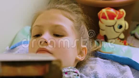 戴着围巾的女孩在床上看书等医生视频的预览图