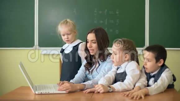 孩子们和老师在教室里讨论和看笔记本电脑视频的预览图