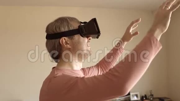 白人男子在家里玩他的手机VR耳机虚拟现实面具在行动4Ksteatam视频视频的预览图