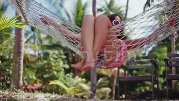 年轻快乐的女人戴着太阳镜躺在吊床上放松享受假期1920x1080视频的预览图