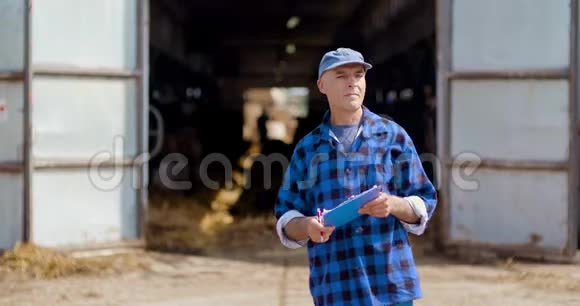 农夫一边打手势一边在剪贴板上对着谷仓写字视频的预览图