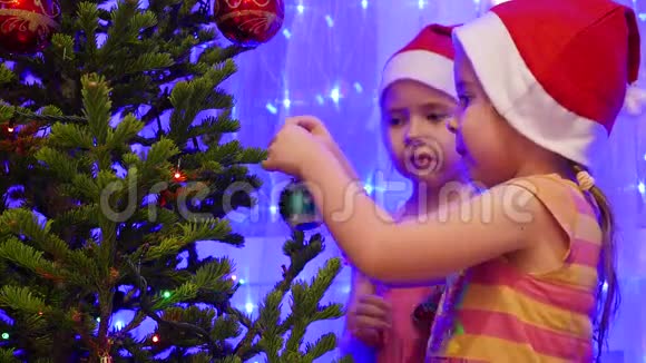 两个姐姐漂亮的女孩用玩具和花环装饰圣诞树视频的预览图