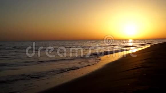 在令人惊叹的温暖的傍晚橙色的日落海景中缓慢而令人满意的平静海浪拍打在沙滩海洋海岸海岸线上视频的预览图