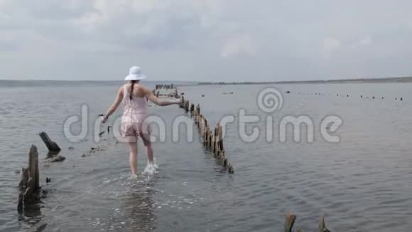穿着漂亮裙子的旅游妇女在水中漫步到地平线上日落旅游体验女孩享受轻松视频的预览图