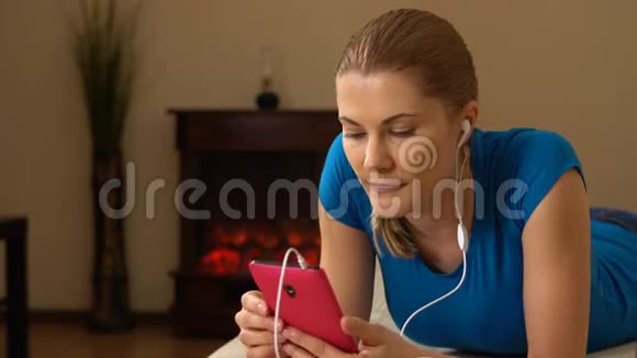 美丽迷人的年轻女人智能手机躺在沙发上听音乐00353视频的预览图