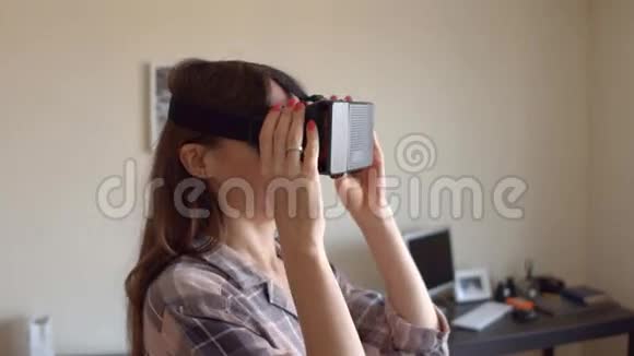 漂亮的黑发女人在家里用她的手机VR耳机实惠的虚拟现实眼镜在行动4K视频的预览图