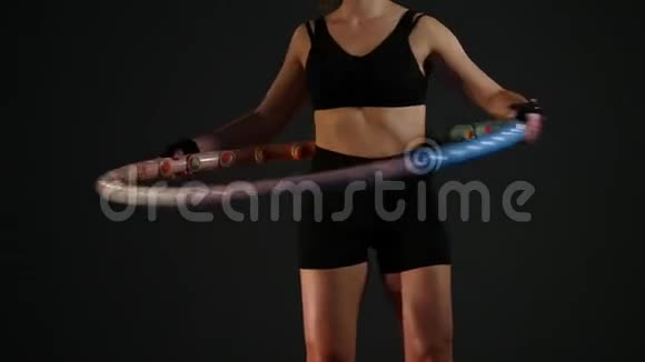 年轻女子在黑色背景下做呼啦圈锻炼视频的预览图