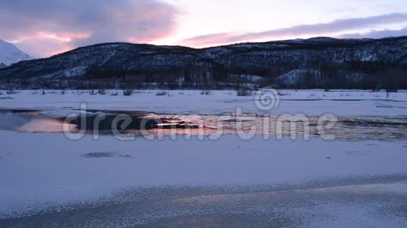 冰冷流动的河流流过河冰的洞粉红色的倒影视频的预览图