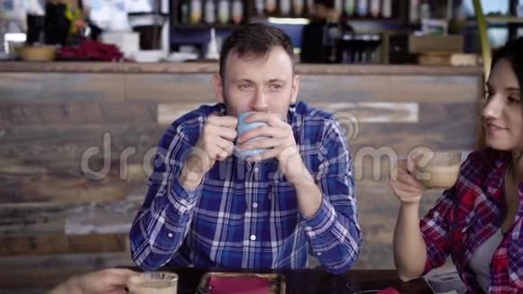朋友们坐在咖啡馆里喝咖啡和茶他微笑着两个漂亮的黑发女人互相交流视频的预览图