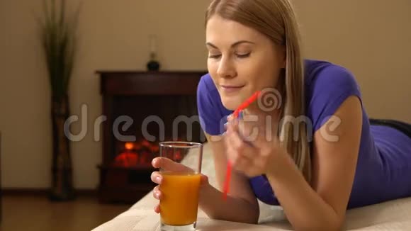 美丽的年轻女人躺在沙发上喝着杯子里的果汁00342视频的预览图