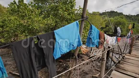 菲律宾贫民窟的穷人之家沼泽从高水板上的木桥鞋带上的衣服视频的预览图