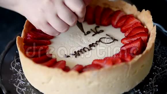 糕点厨师装饰一个芝士蛋糕上面有草莓上面有烹饪袋和棕色奶油视频的预览图