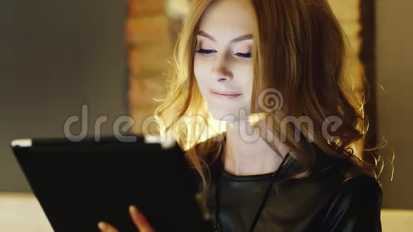 一位美丽的年轻女子在咖啡馆里享受着平板电脑视频的预览图