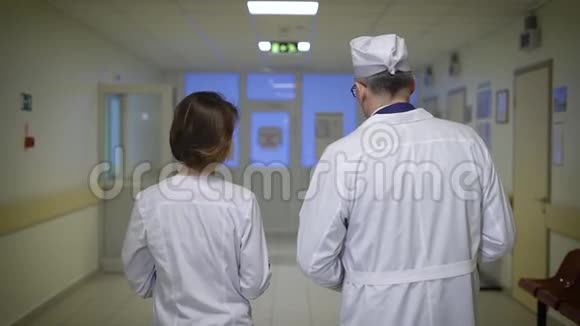 医生一男一女走上医院走廊相互交流医务人员把文件夹放在视频的预览图