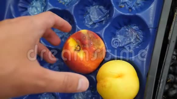 一个人在一个蔬菜货架上的超市里买蔬菜和水果一个人从腐烂的水果中选择桃子慢慢视频的预览图