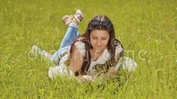 美丽的黑发长发躺在绿草上微笑着享受大自然视频的预览图