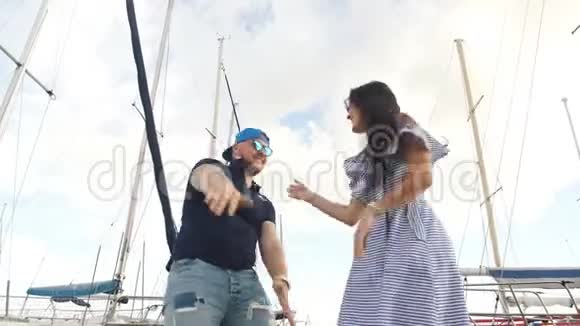 一对漂亮的年轻夫妇在游艇港口散步跳舞视频的预览图