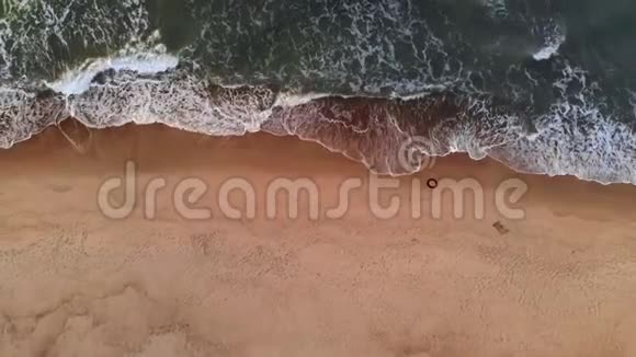 鸟瞰日落时热带海滩的一段视频展示傍晚的空中拍摄的绿色泡沫海浪拍打的画面视频的预览图