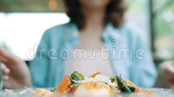美丽快乐的亚洲女人在餐馆或咖啡馆吃一盘意大利海鲜意大利面微笑着看着食物视频的预览图