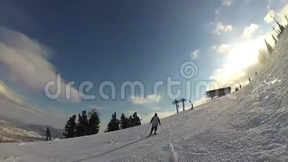 阳光明媚的一天一个滑雪爱好者滑下山坡视频的预览图