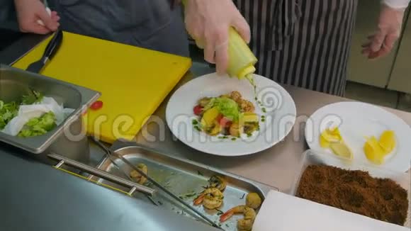烹饪学员观看厨师添加酱汁和香料的新鲜沙拉与虾视频的预览图