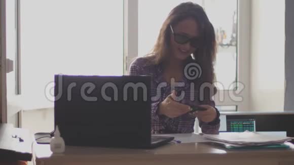 女商人戴着眼镜在笔记本电脑和电话上工作慢动作3840x2160视频的预览图
