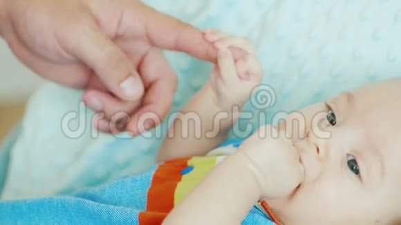 宝贝拿着他父亲的手指啃着他的拳头概念支持和照顾父母视频的预览图