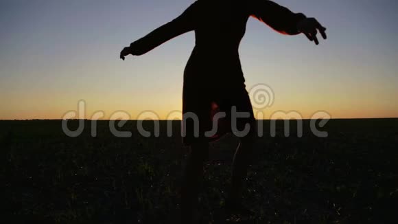 日落时在田野里奔跑跳舞的女孩的剪影视频的预览图