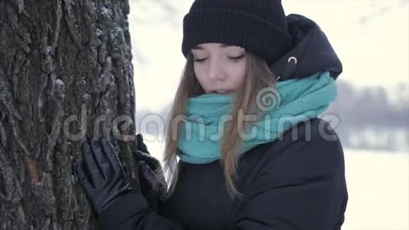 快乐的女孩穿着温暖的衣服站在树附近全高清视频视频的预览图